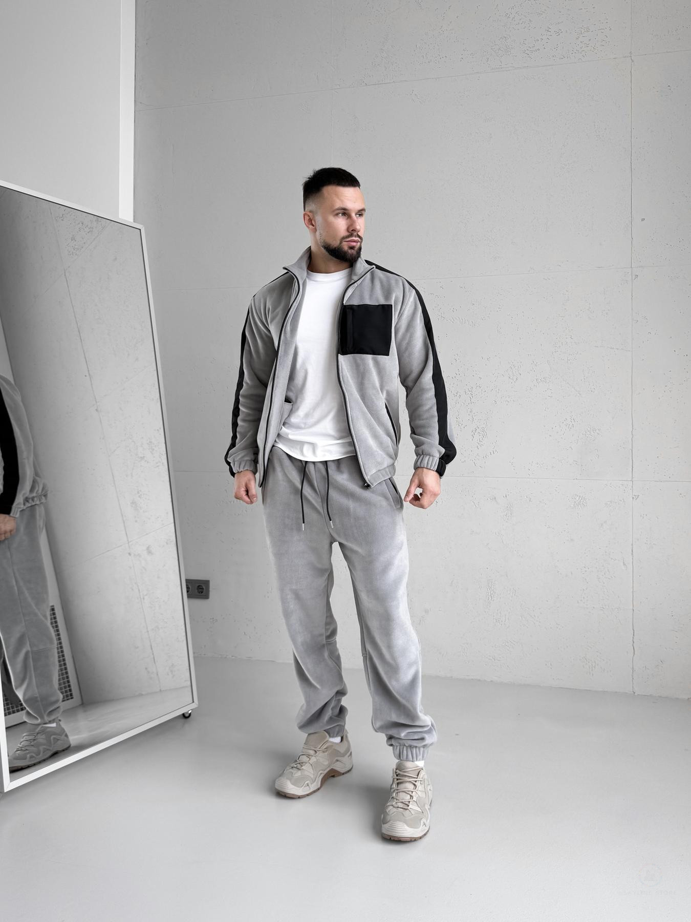 Зимовий чоловічий спортивний костюм Move світло-сірого кольору з турецького флісу полар, вид спереду на моделі, демонструються 5 кишень на блискавках та капюшон.
