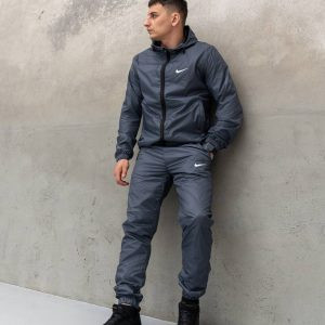 Чоловічий вітрозахисний спортивний костюм Nike темно-синього кольору, виготовлений з водовідштовхувальної європлащівки, з повною застібкою. Класичний крій для осінньо-весняного сезону, що захищає від вітру та дощу.