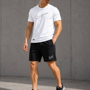 Зображення: Чоловічий літній спортивний комплект Nike, що складається з темно-сірої футболки з логотипом та чорних шортів, виконаних з дихаючого куліру та двонитки для комфорту в спеку.