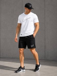 Зображення: Чоловічий літній спортивний комплект Nike, що складається з темно-сірої футболки з логотипом та чорних шортів, виконаних з дихаючого куліру та двонитки для комфорту в спеку.